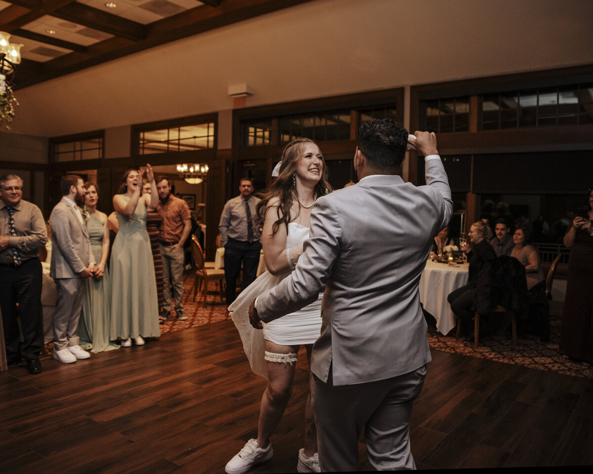 A joyful dance at a celebration as a couple takes the floor, with guests looking on in the background taken by jen Jarmuzek photography a Minneapolis wedding photographer