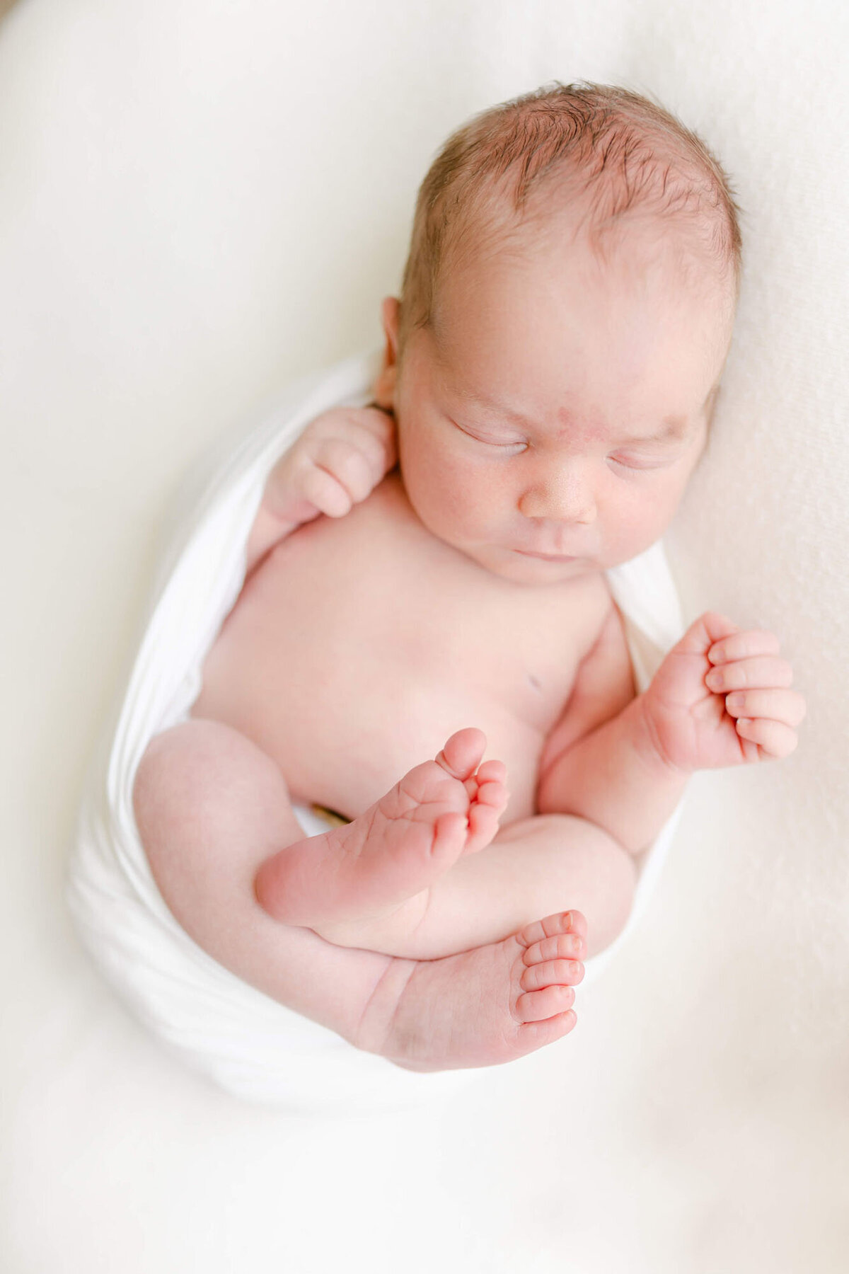 Soft natural light portrait by a newborn photographer Bay Area, baby sleeping on bed.
