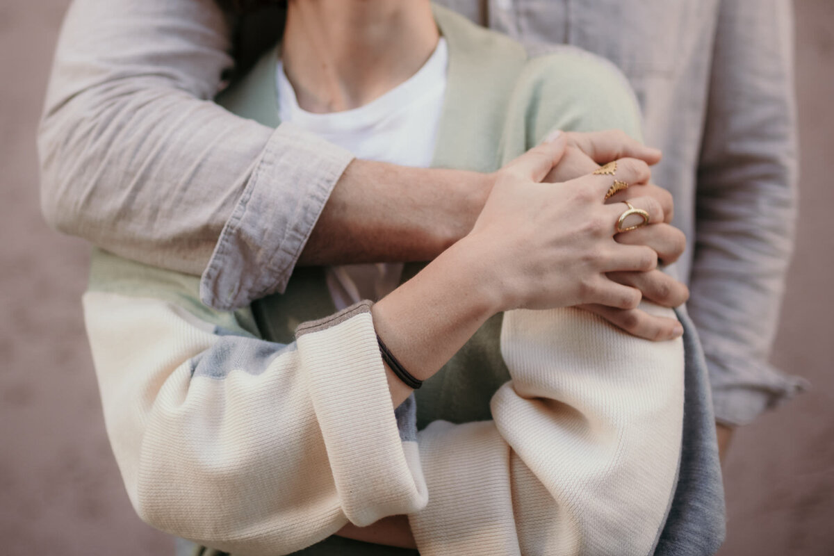 A closeup of a couple holding hands in a tight embrace.
