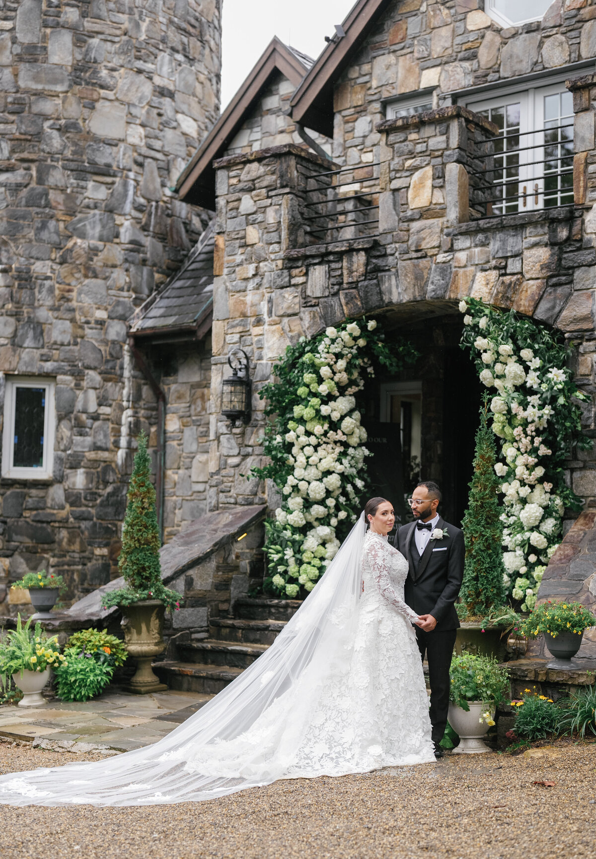 Bride and groom standing in front of the floral-covered stone entrance at Castle Ladyhawke during their fall mountain wedding.