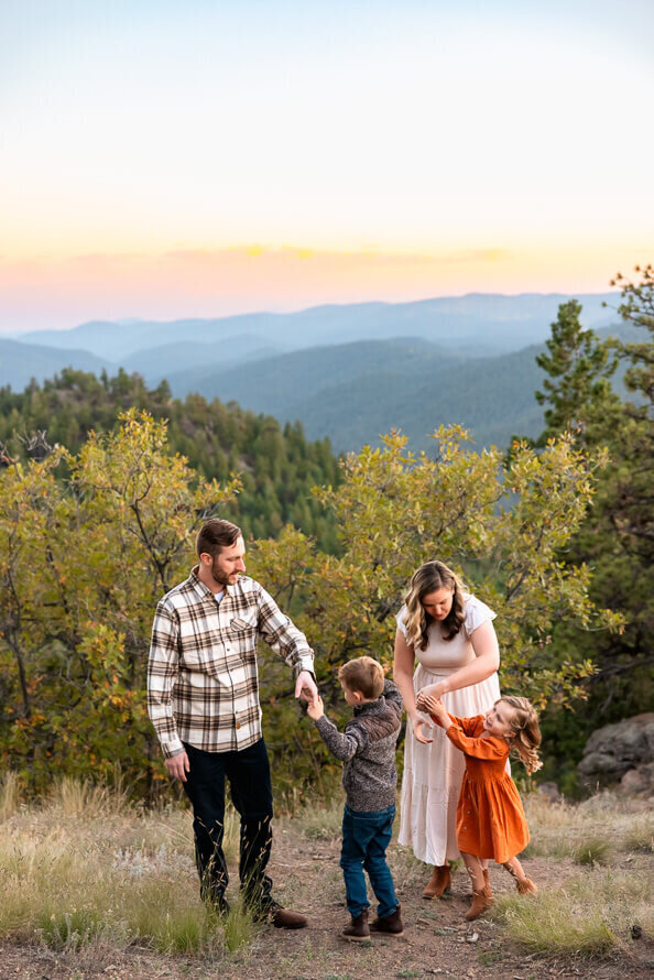 A family of four dances with the Rocky Mountains in the background.