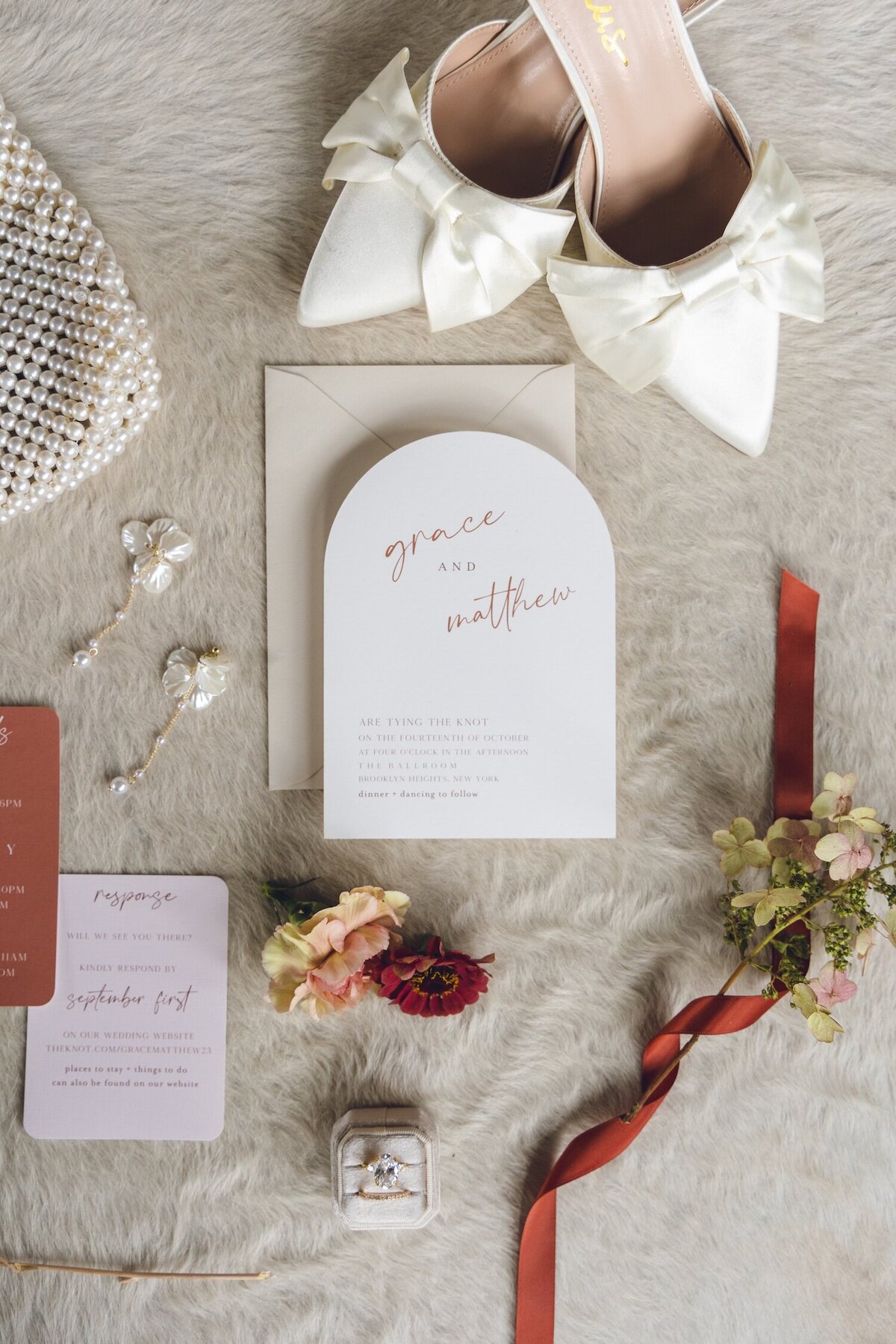 Detail shot of wedding flatlay with pearl heels and invitation