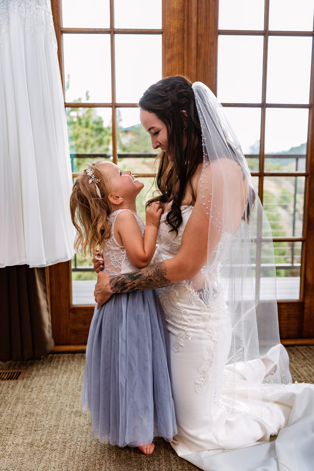 Shannon Lee, from Love Like Wild Photography, captures a sweet moment between a bride and a young girl smiling at each other.