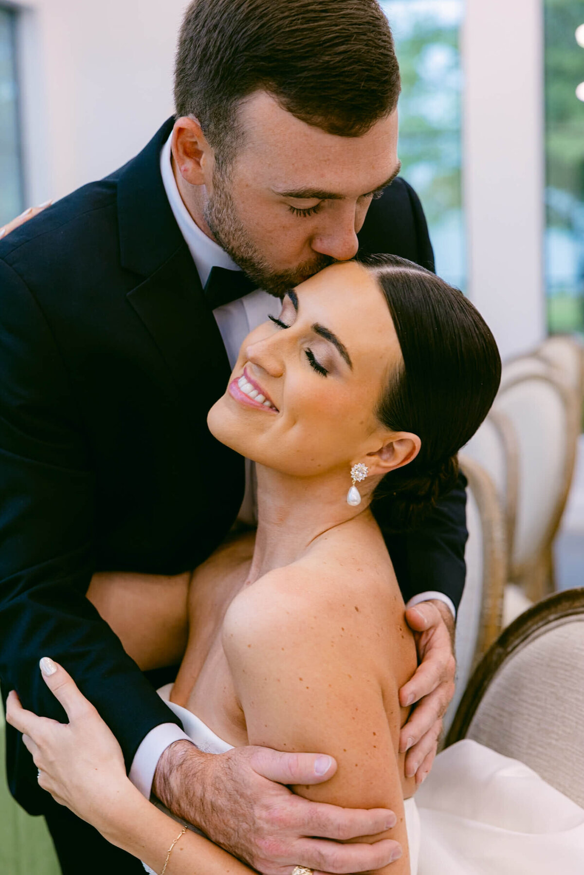 A wedding day photo of the groom kissing his bride on the head