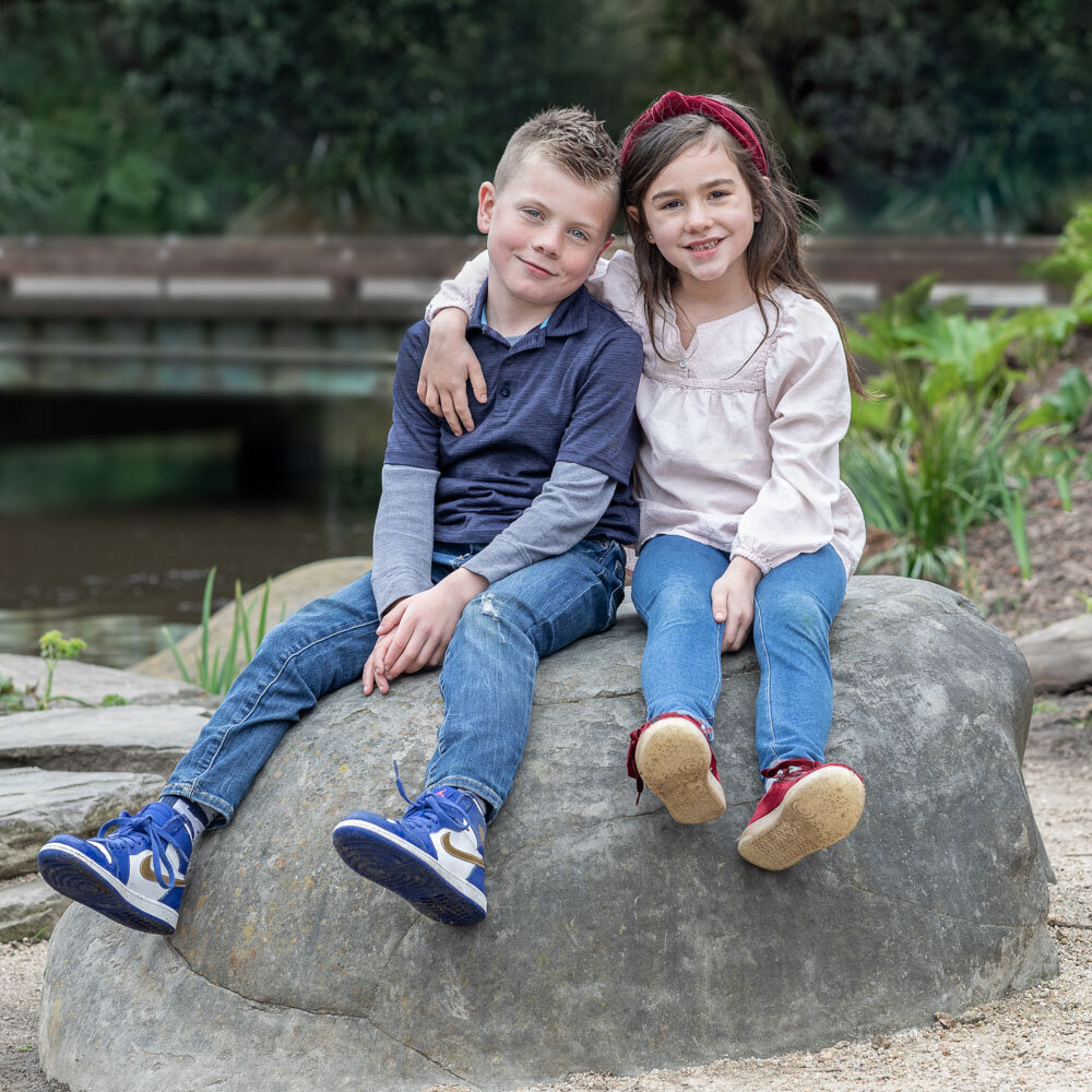 siblings smiling on rock