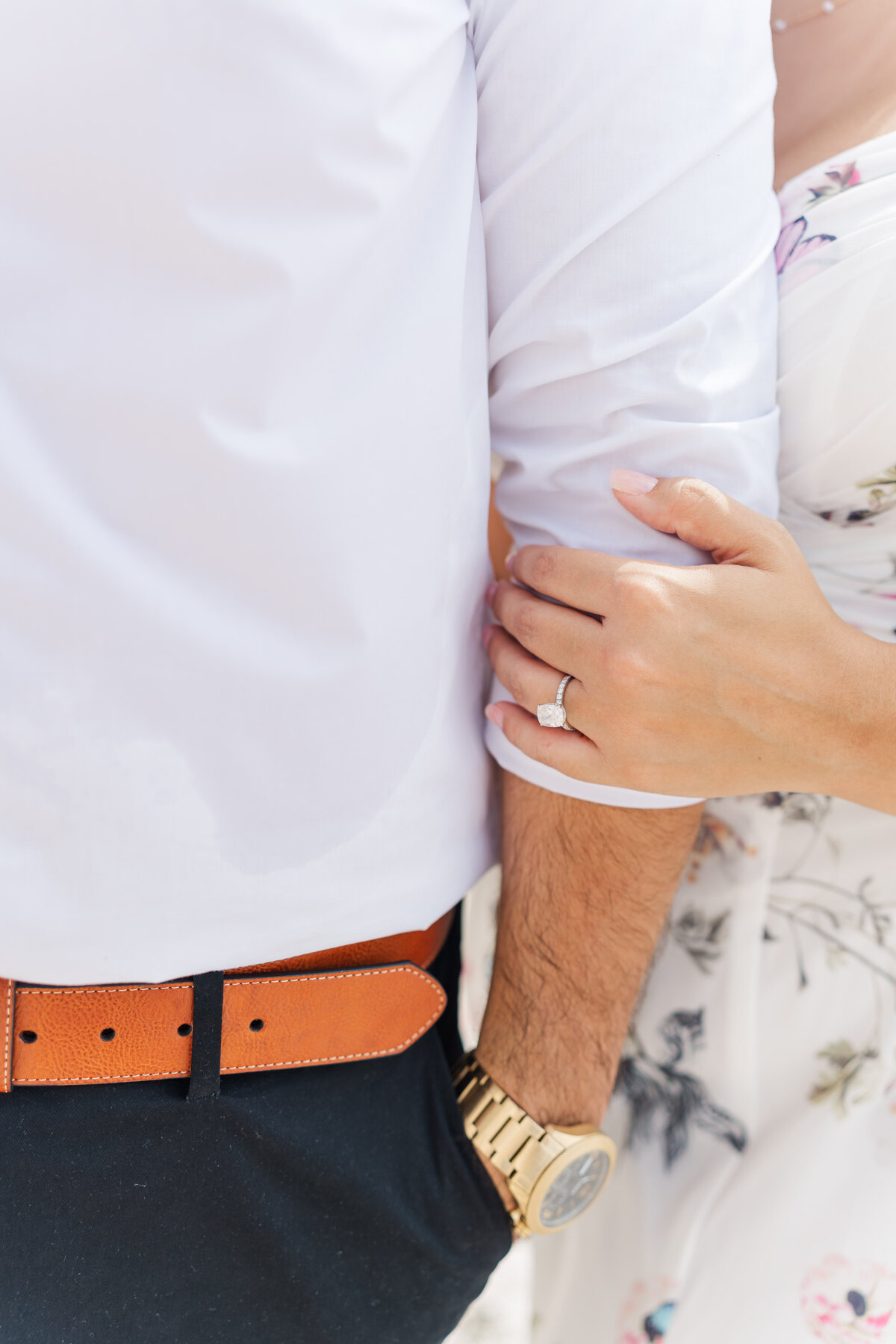 a womans hand witha an engagement ring touching a mas's  arm