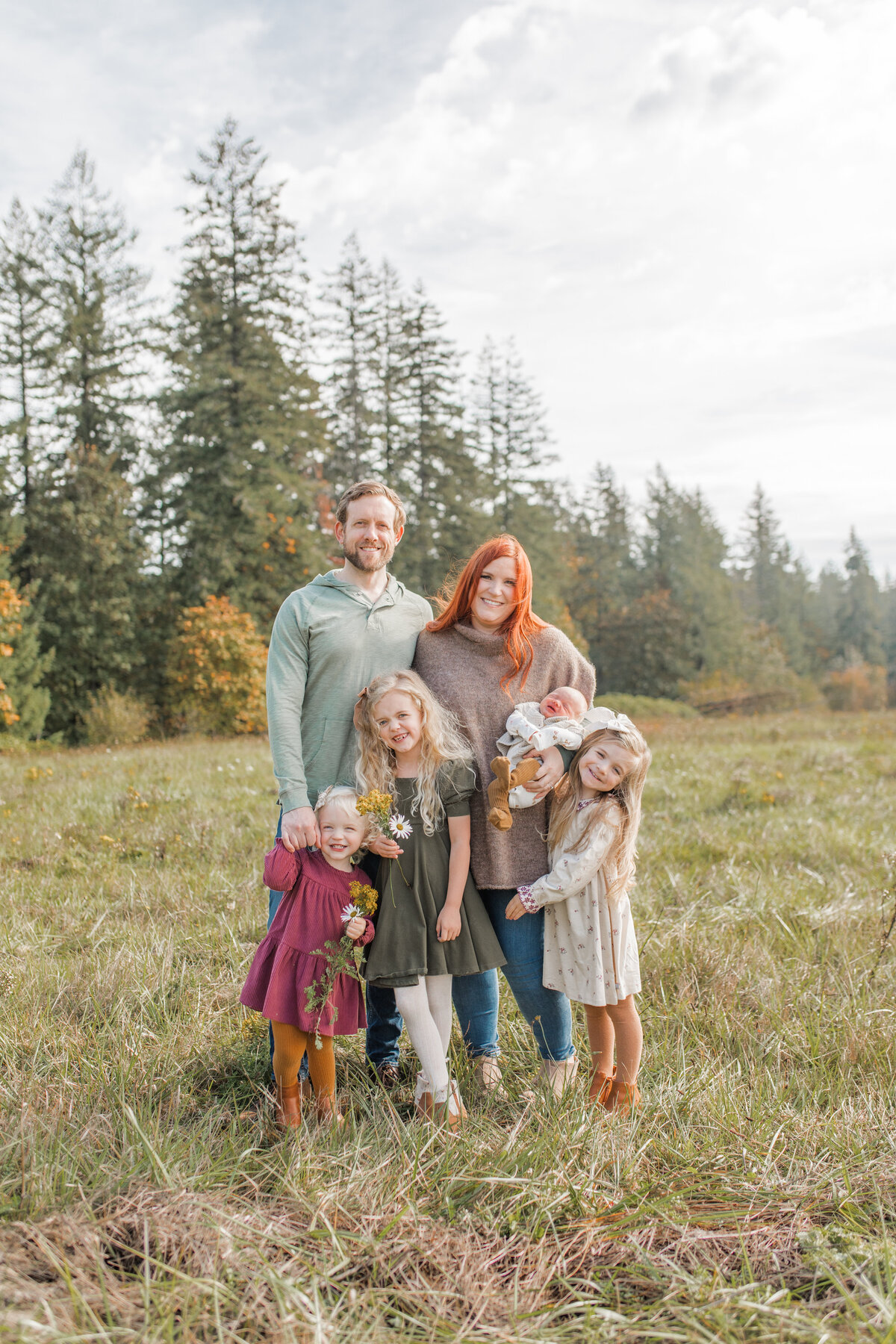Family standing in a field, parents with three young girls