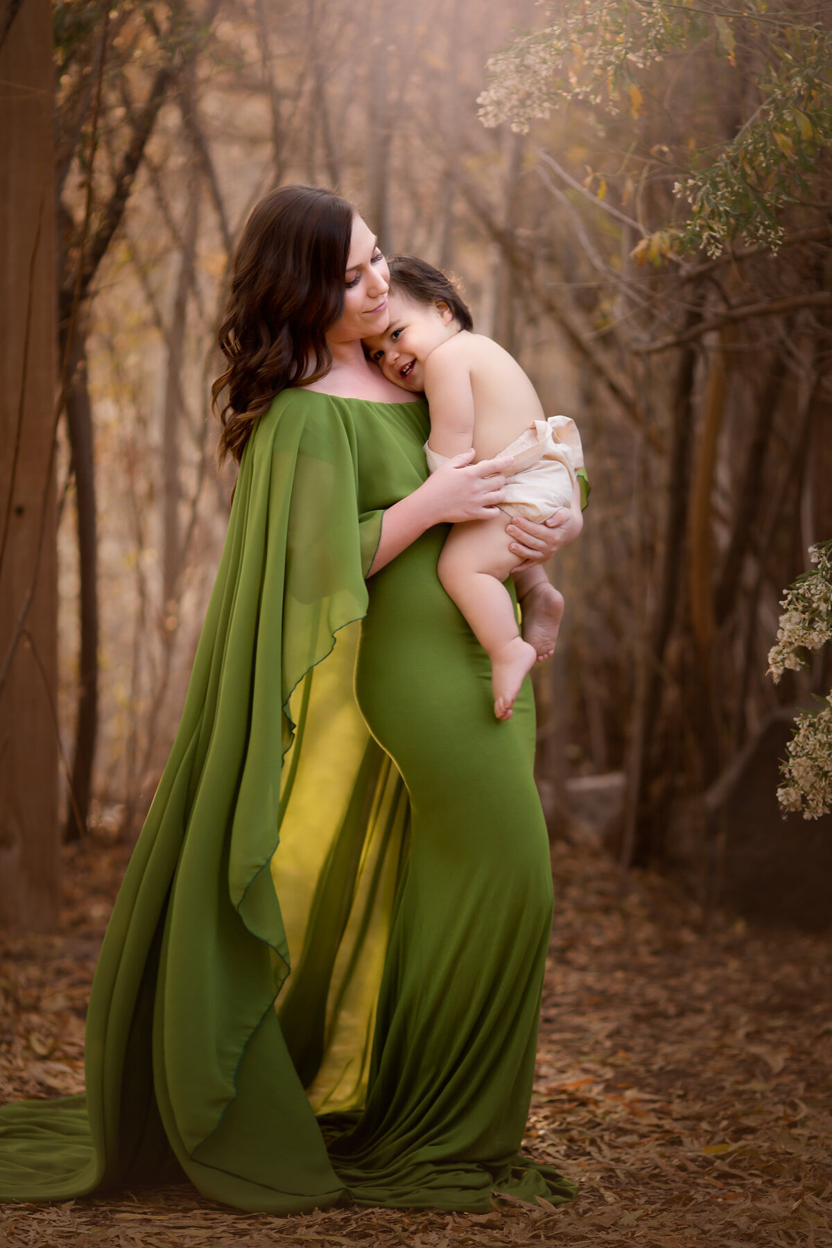 A Dallas family photographer captures a tender moment between mother and child, showcasing their bond in a serene outdoor setting with a beautiful flowing green gown.