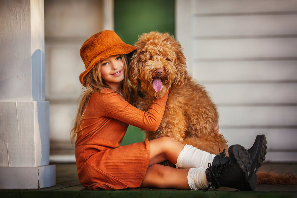 Esme in her golden outfit is holding her golden doodle best friend dog.