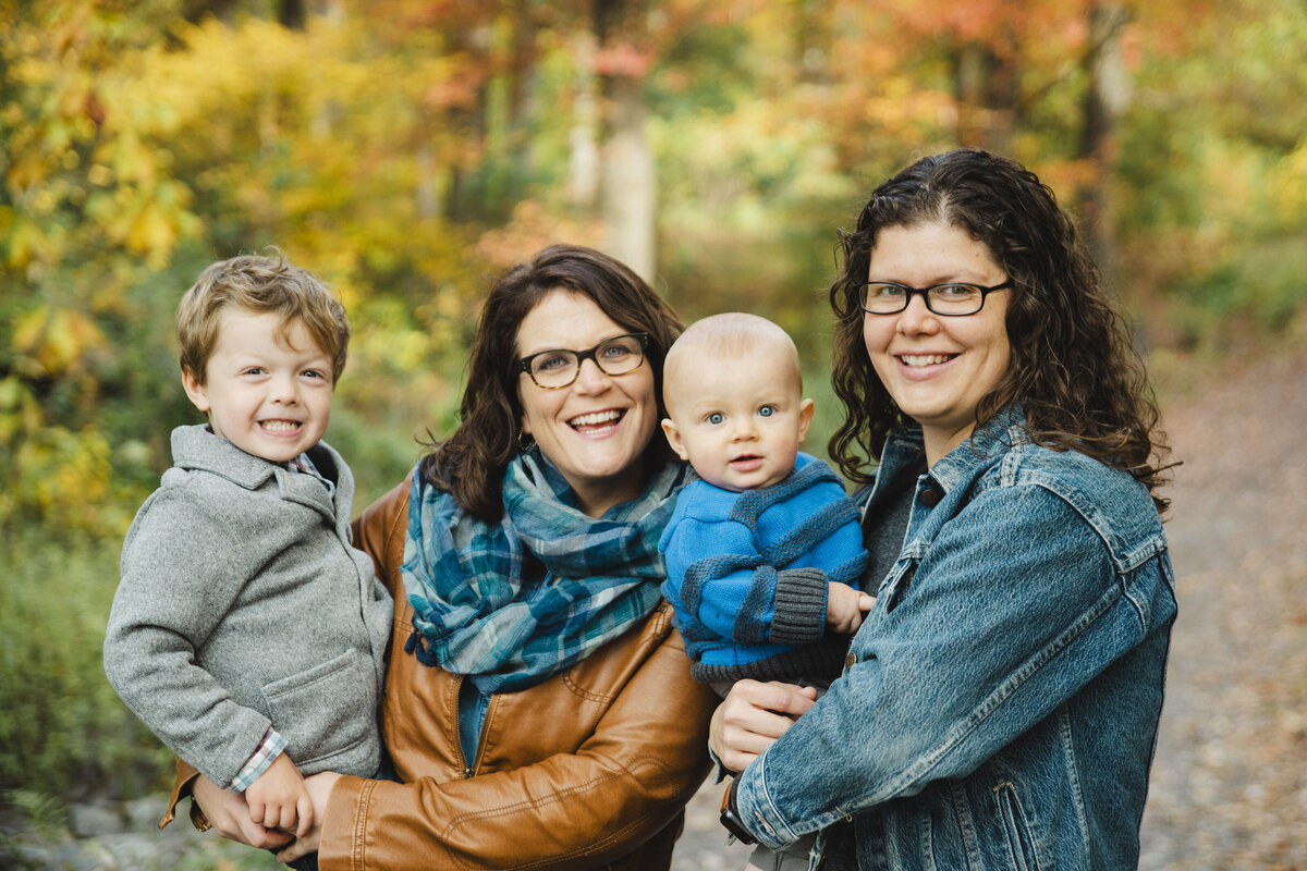 A family of four smiles in a forest.