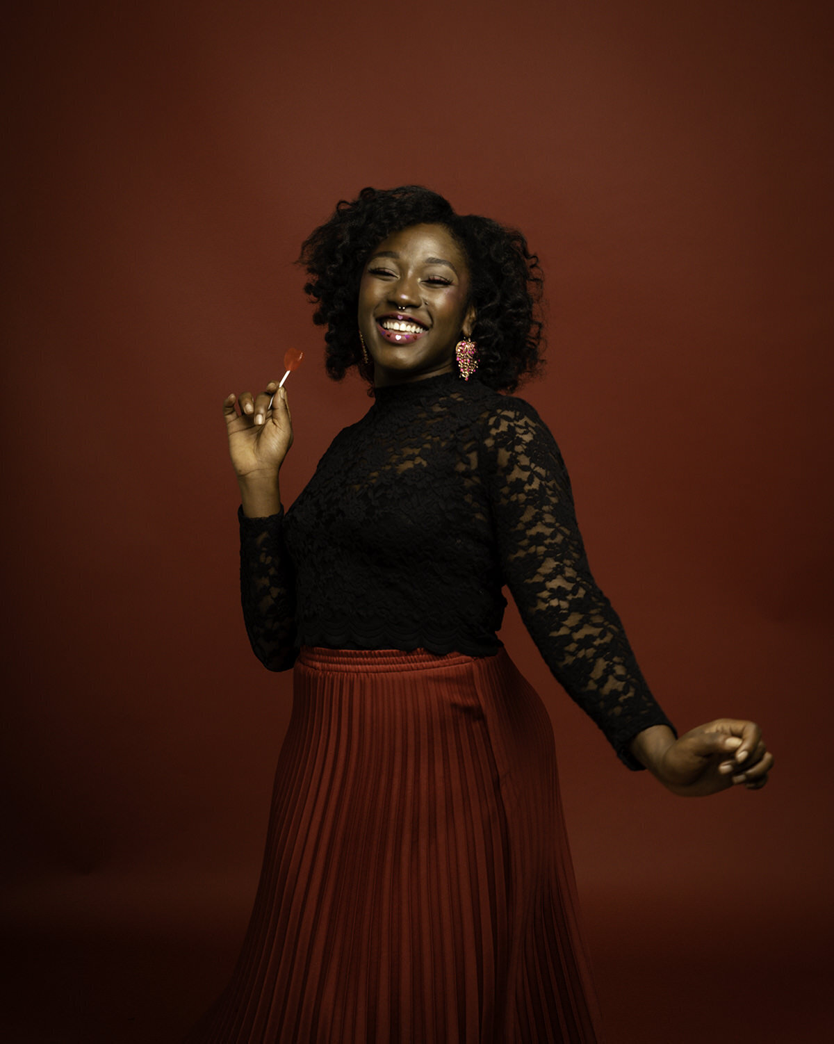 Black woman in lace black shirt and red skirt smiling