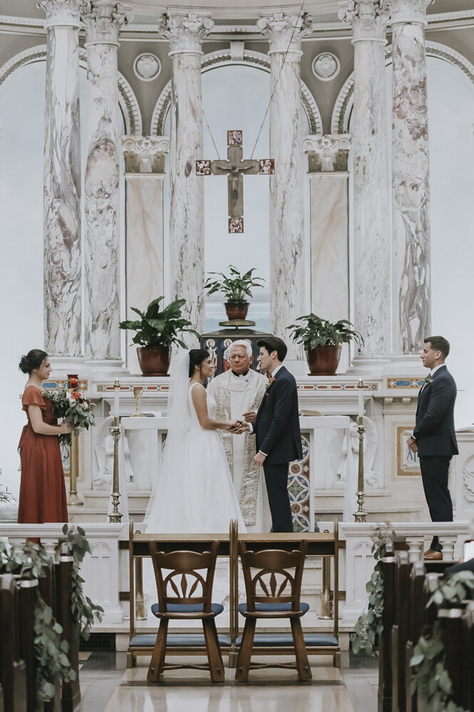 bride and groom standing with priest