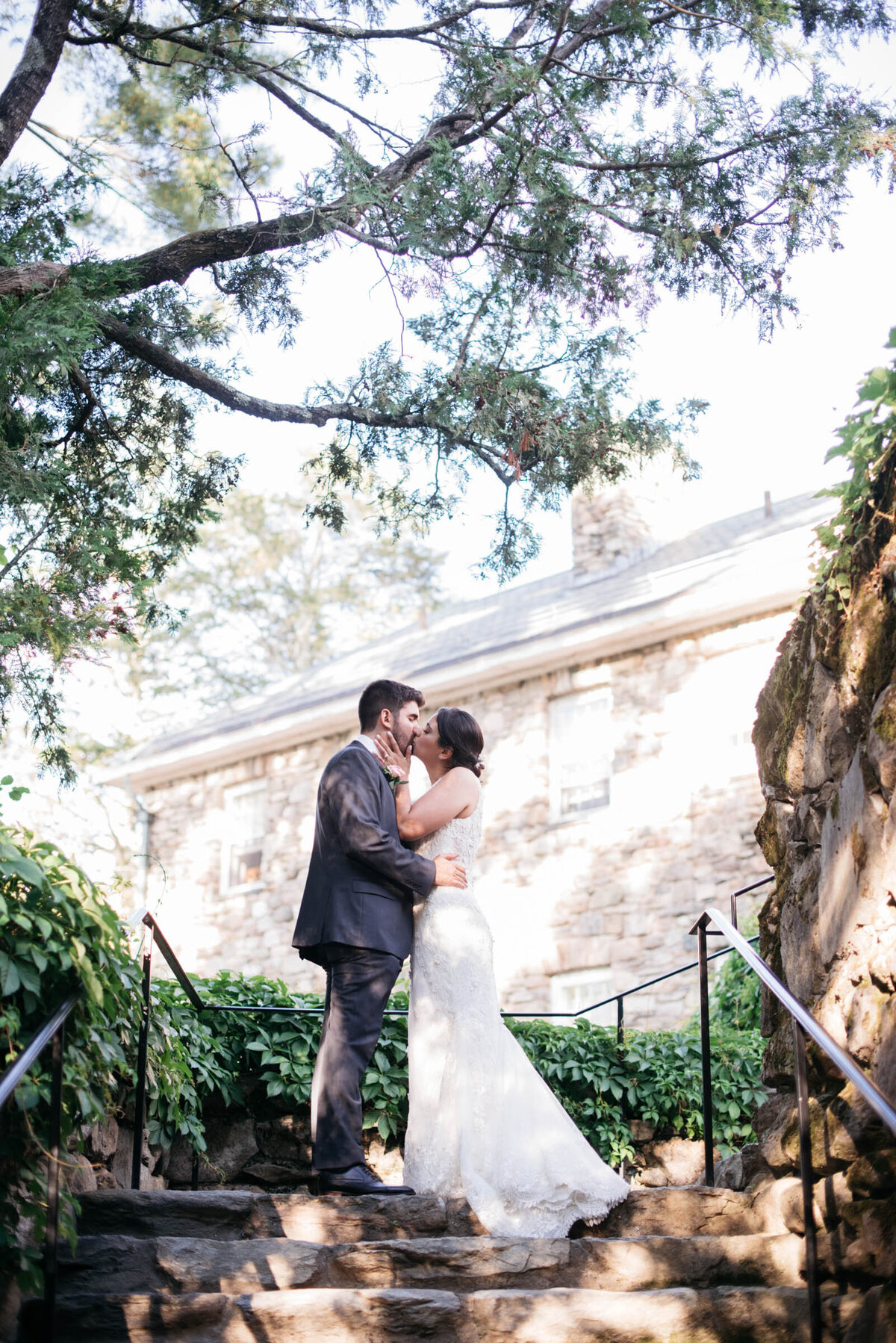 bride and groom kissing at the top of stone stairs at the connors center wedding