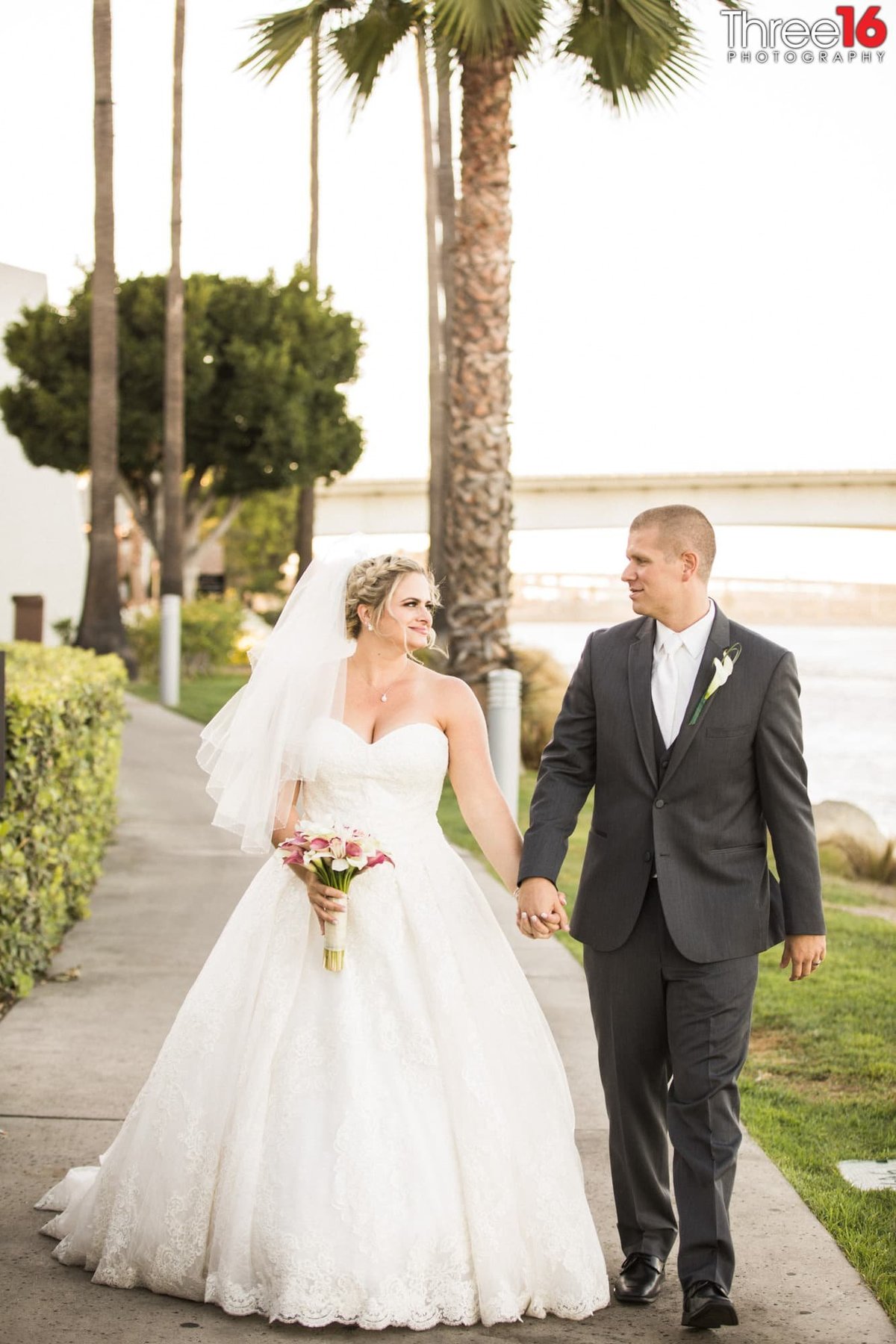 Bride and Groom hold hands and go for a walk near the coast