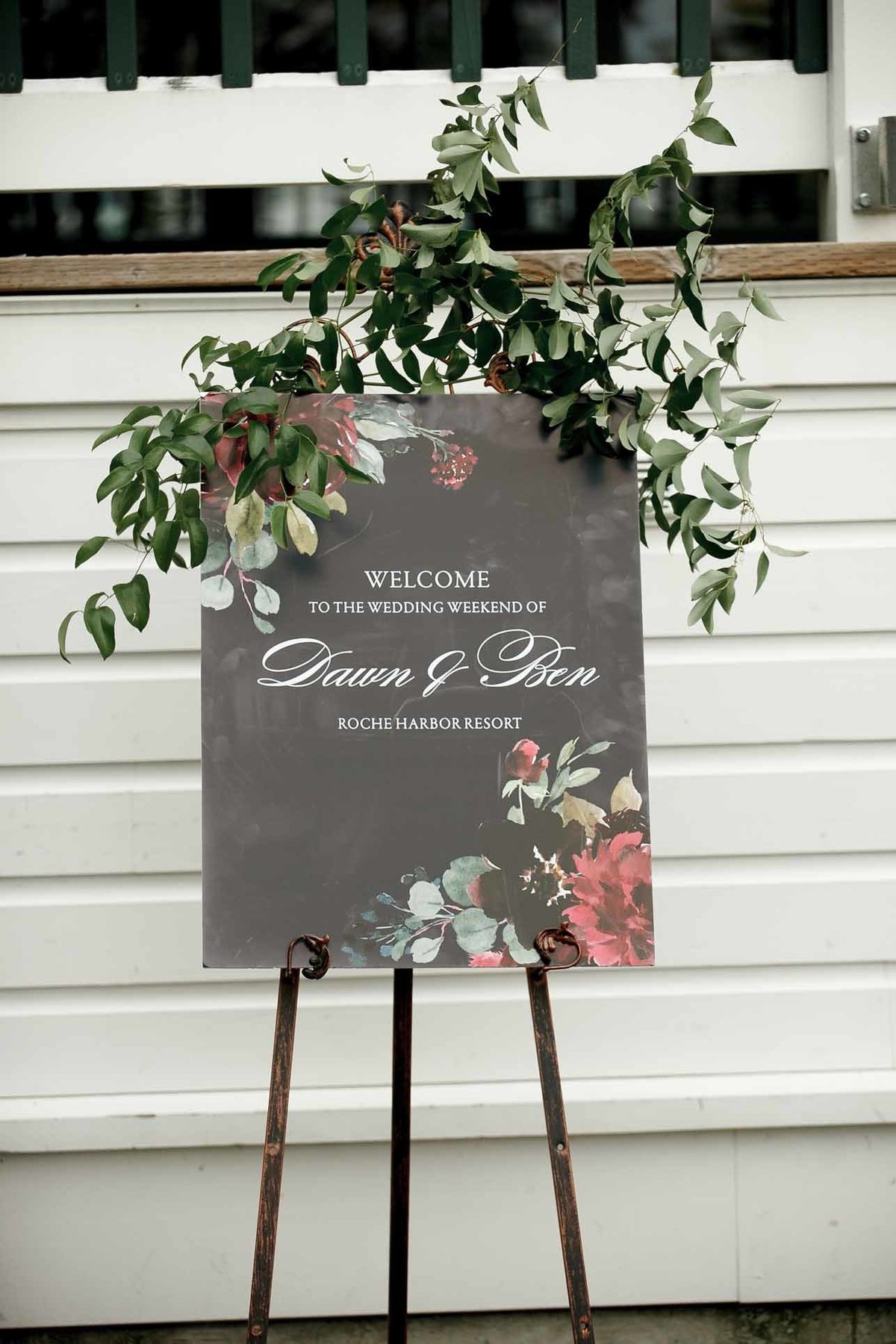 a welcome sign for wedding decorated with greenery and flowers