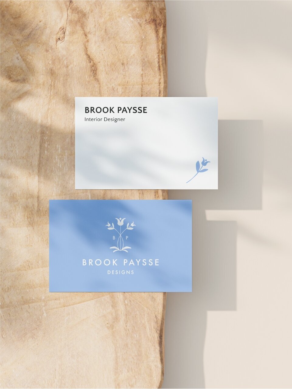 Dual business card layout for Brook Paysse—one side featuring name and title on white with floral icon, and the other with logo on coastal blue.