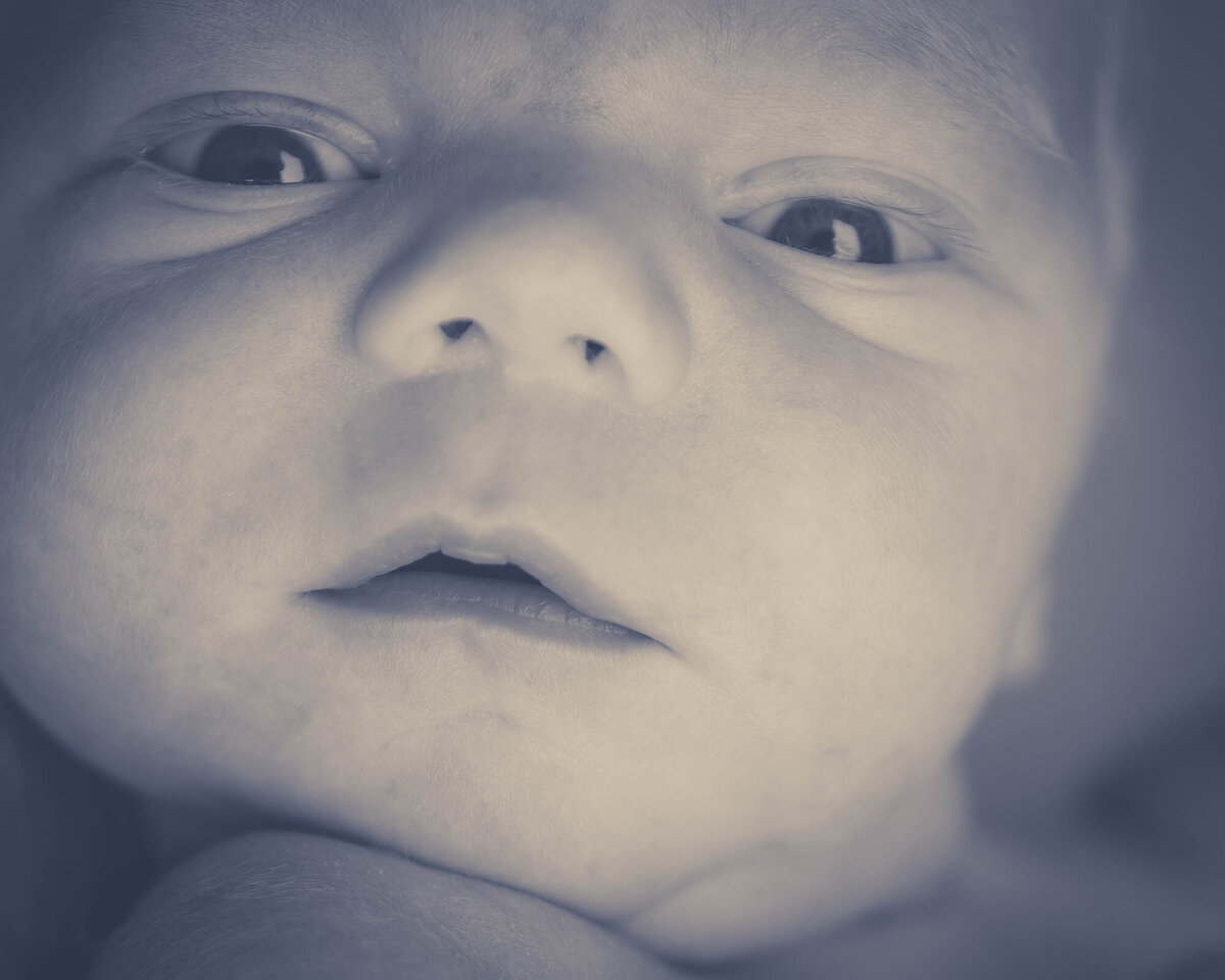 Closeup image of a newborn baby's face with dramatic lighting