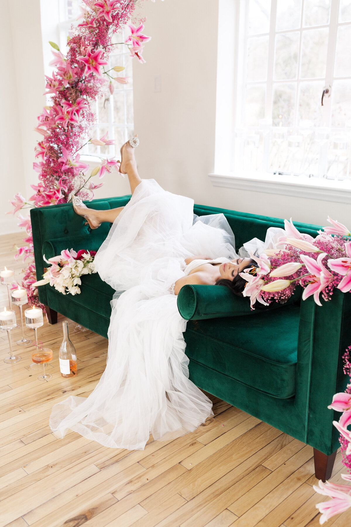 bride lying on an emerald green sofa with pink and white florals