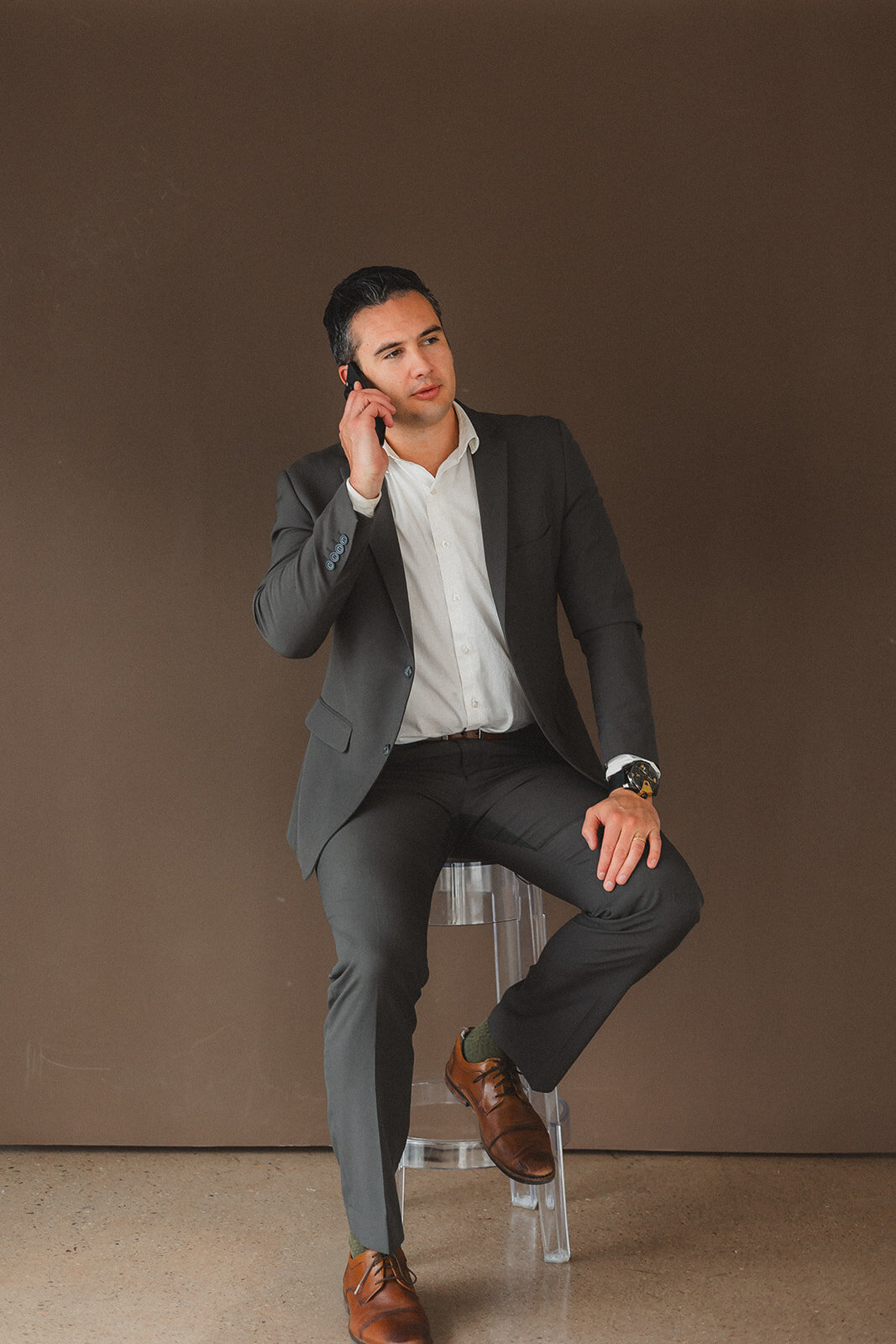 A man sits on a stool on the phone