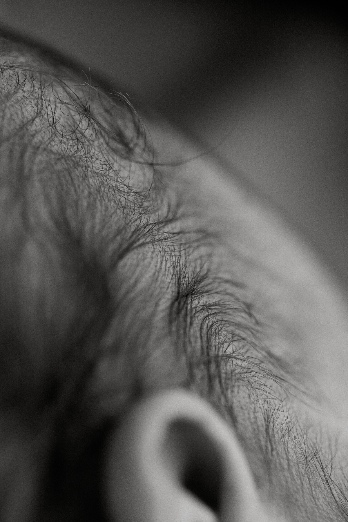 A close up of a newborn babies hair in black and white showing how beautiful a babies hair during her newborn photoshoot with top newborn photographer lucy jane