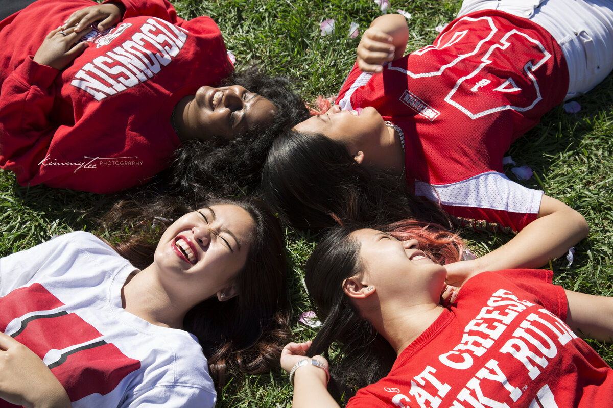 Four girls laying in grass wearing Wisconsin Badger shirts