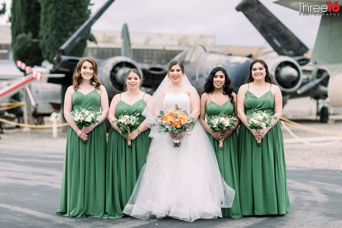 Bride poses with her Bridesmaids on the grounds of the Planes of Fame Air Museum