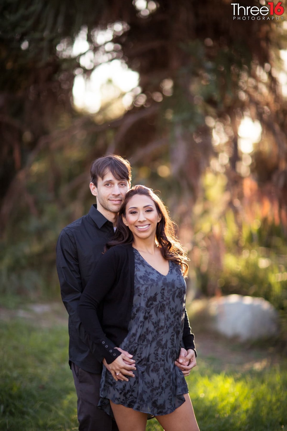 Engaged couple pose for the photographer with finger interlinked together