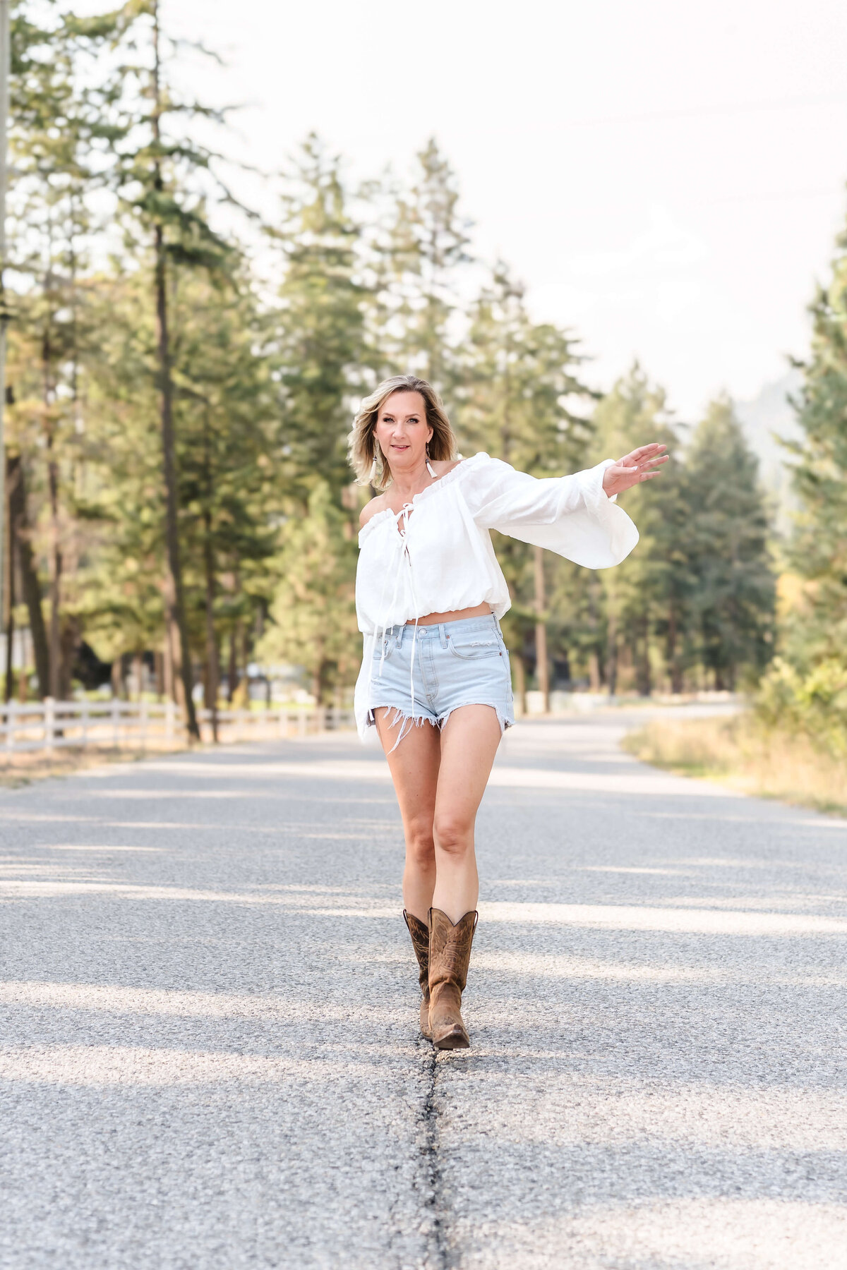 carefree woman dancing down a deserted country road