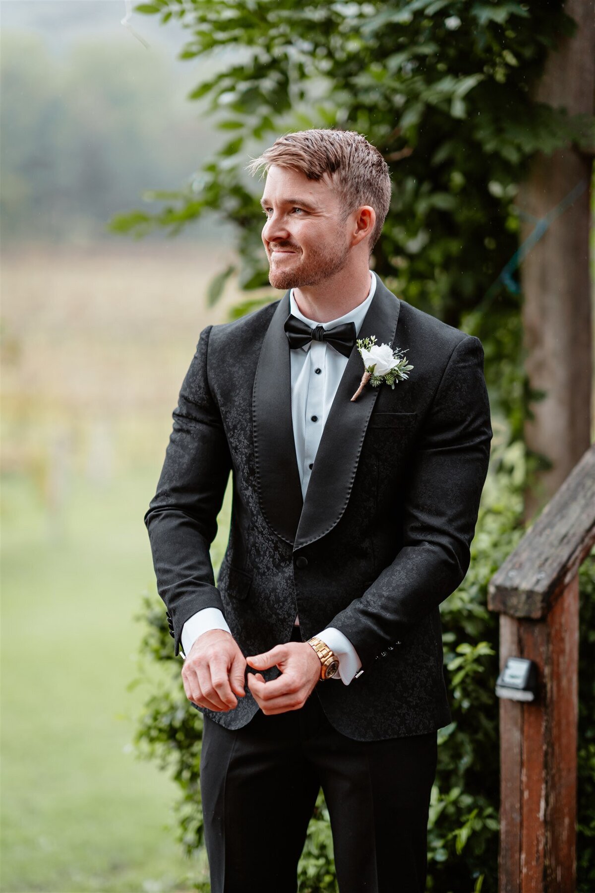 A sharply dressed groom poses amidst picturesque scenery during a photoshoot, exuding elegance and anticipation.