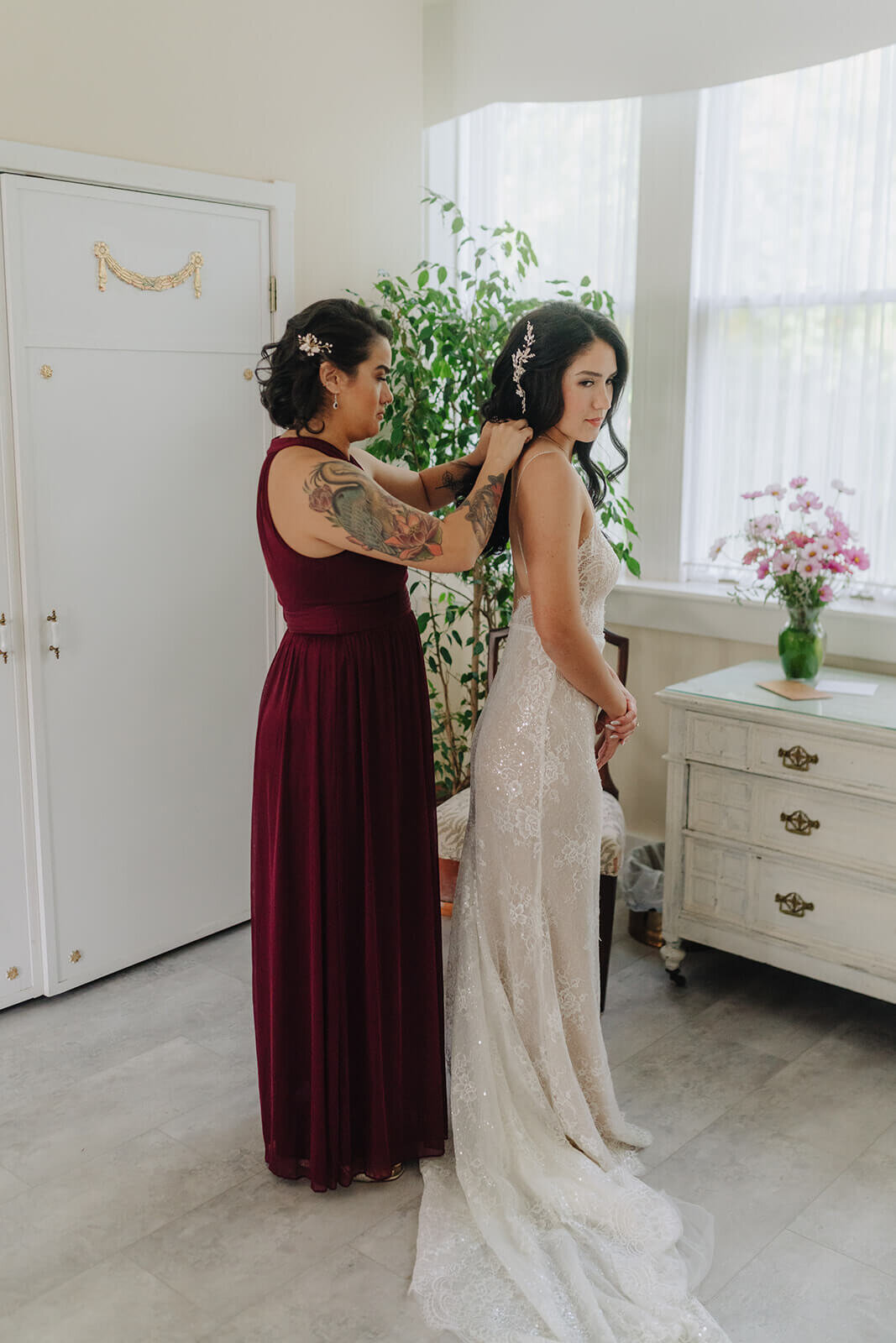 Bridesmaid helping with brides dress