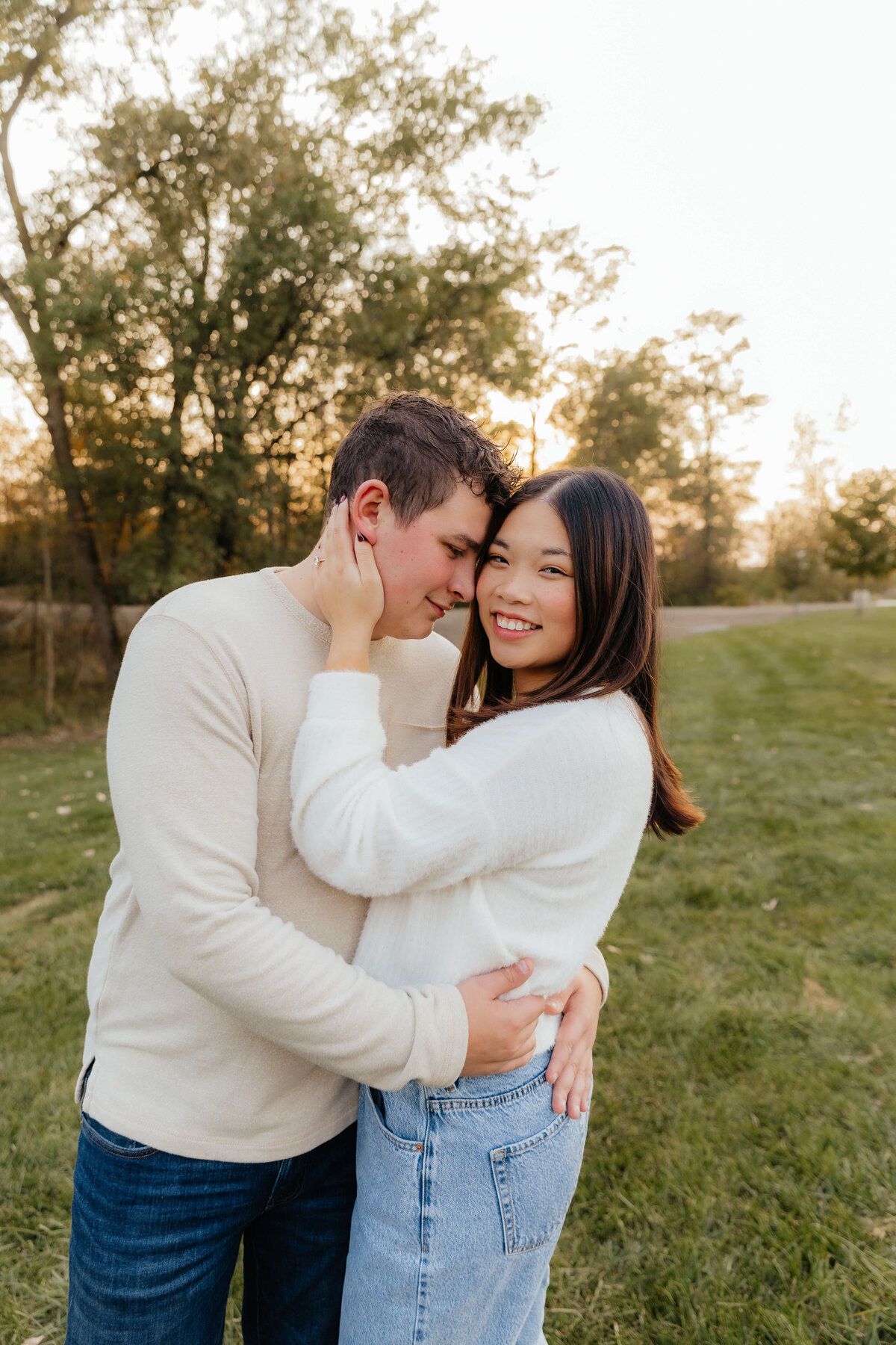 Couple cuddling at sunset in neutral sweaters, cozy Ohio engagement photography for couples who want relaxed, emotion-filled portraits