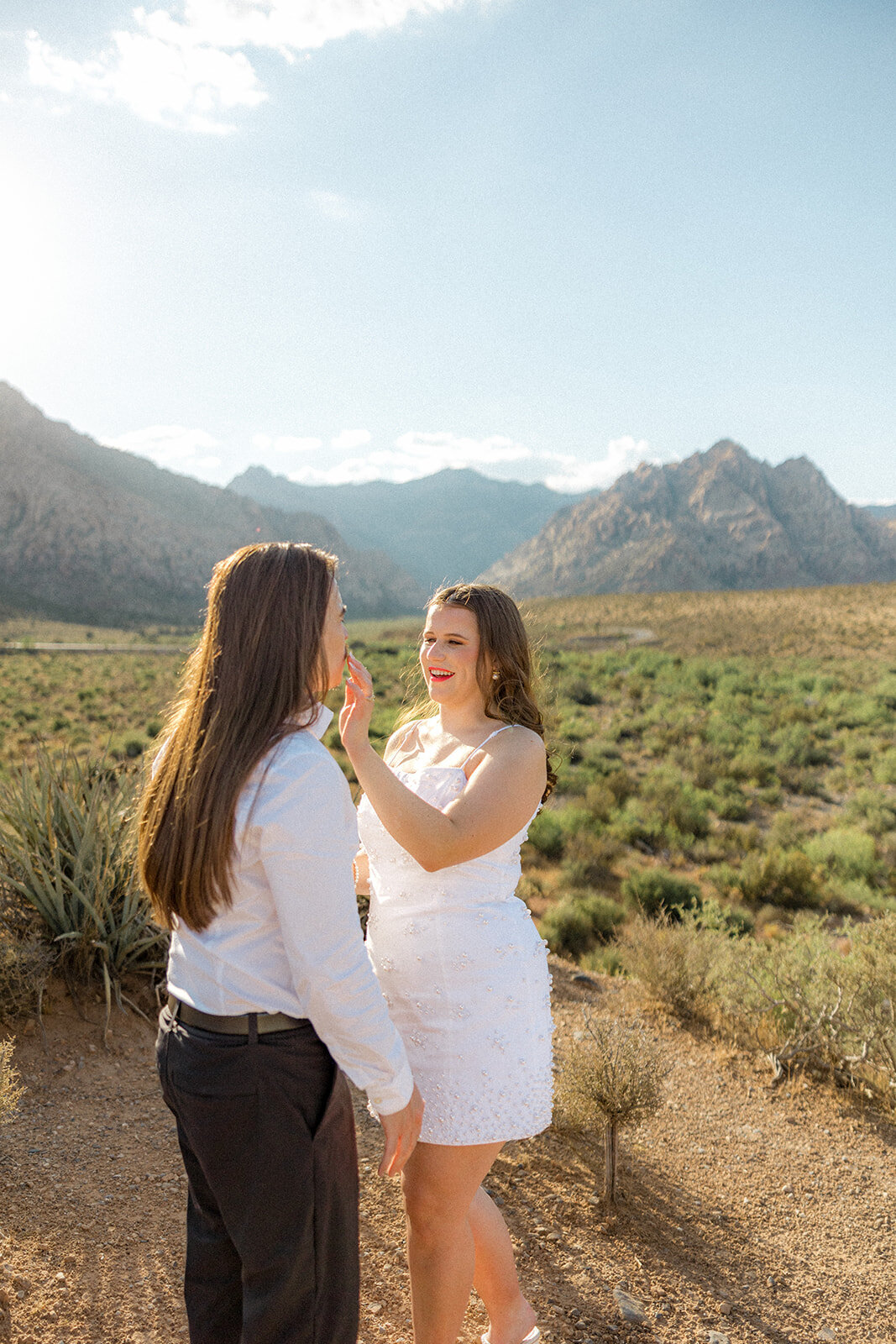 Woman wiping her fiance's lip with mountains in the back in Nevada