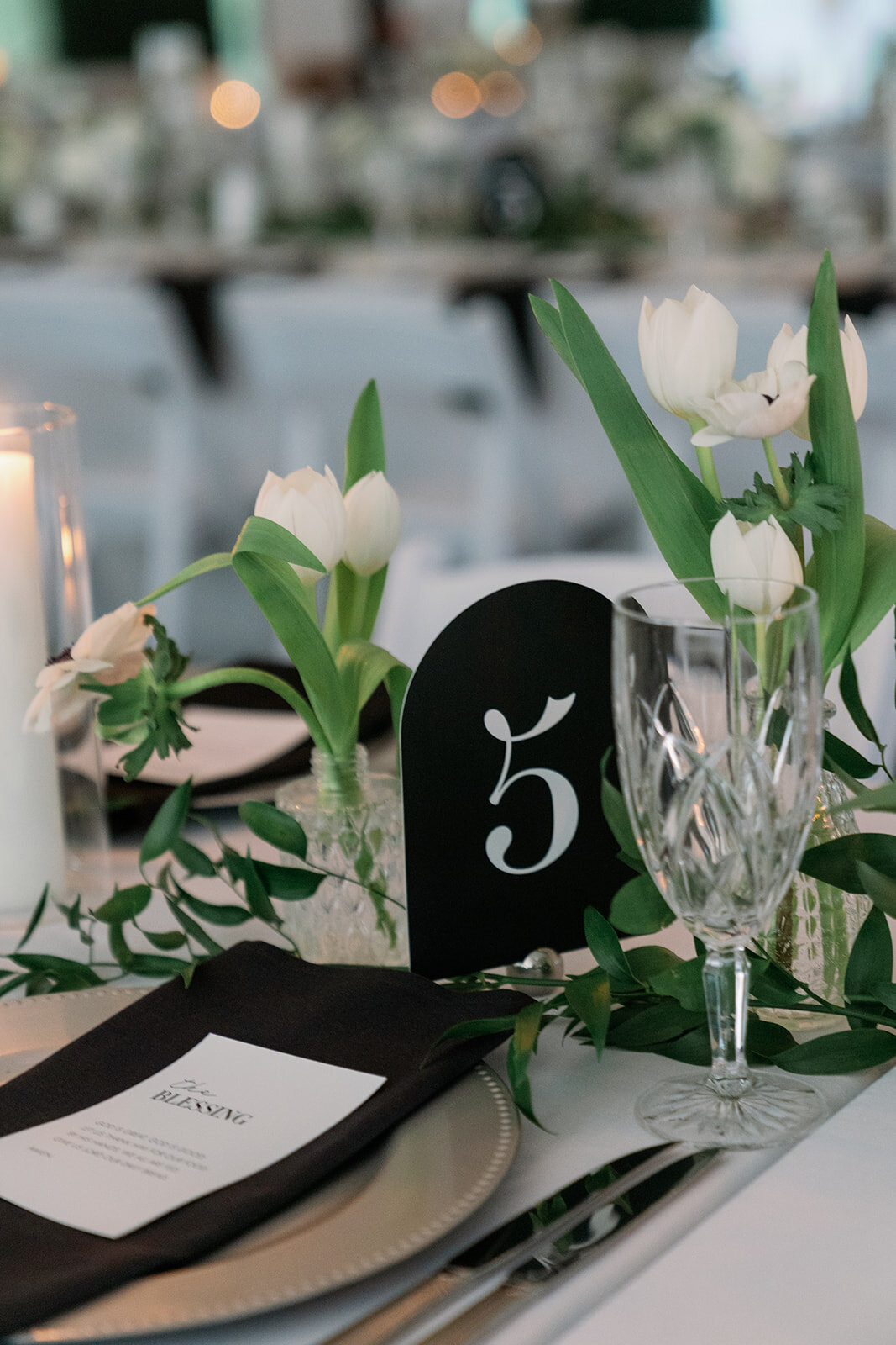 Elegant black table number with white tulips and greenery at The Morris Estate reception.