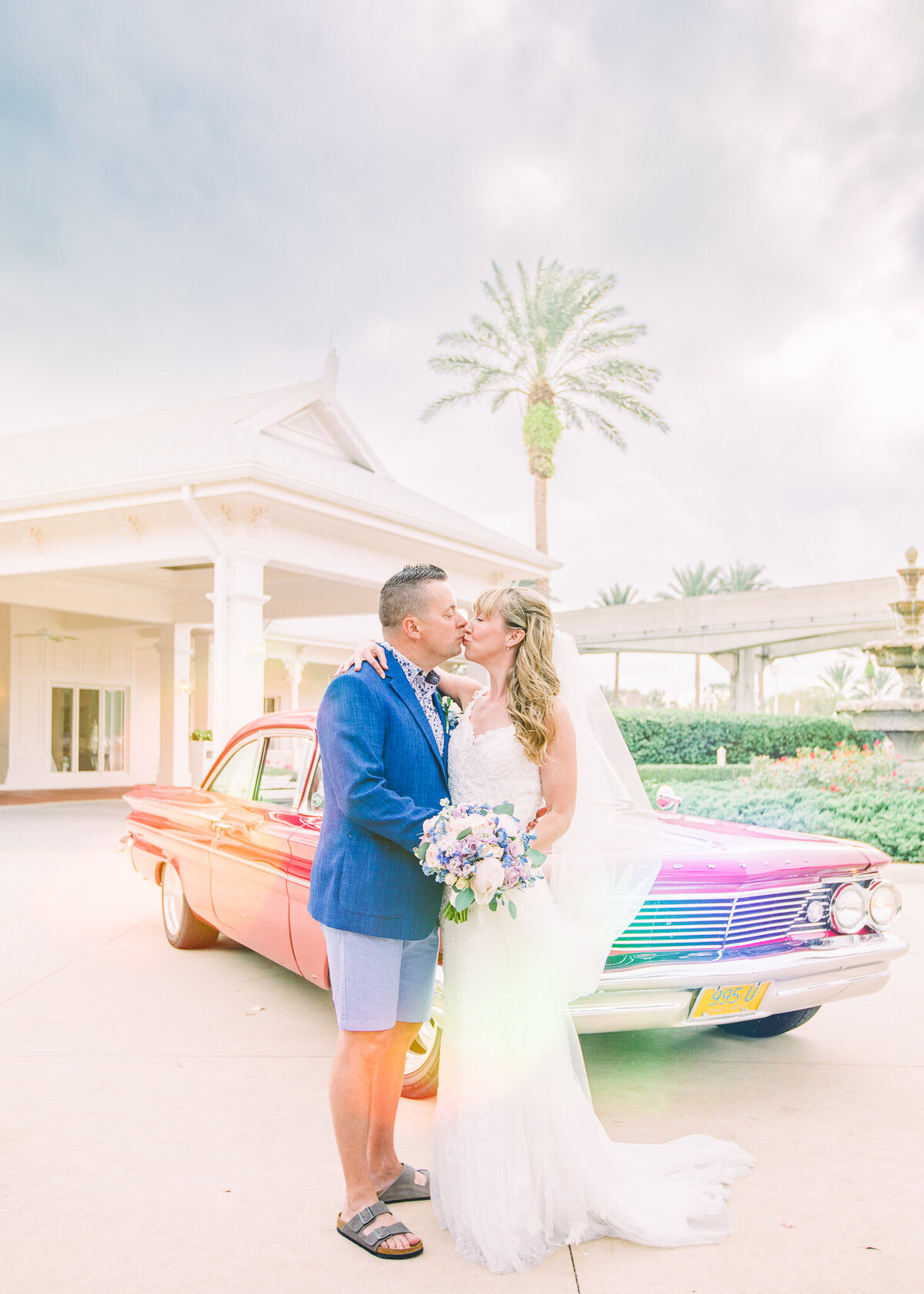 Disney Wedding with bride and groom kissing in front of a vintage car at Disney's wedding pavilion