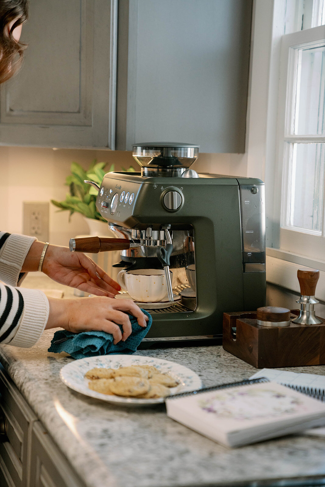 Woman making coffee with an espresso machine in a kitchen during the planner company branding session in Indiana.