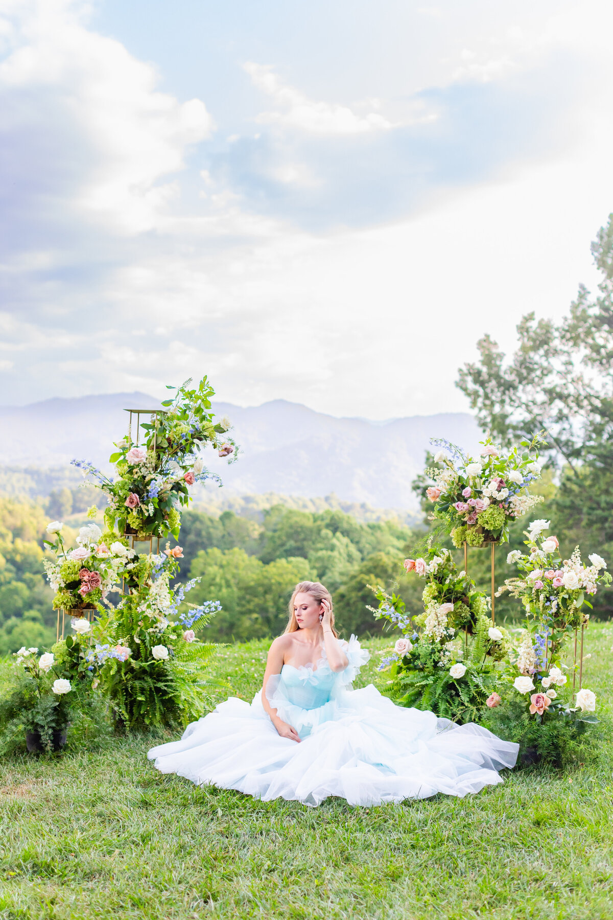 bride sitting in the grass with blue wedding dress