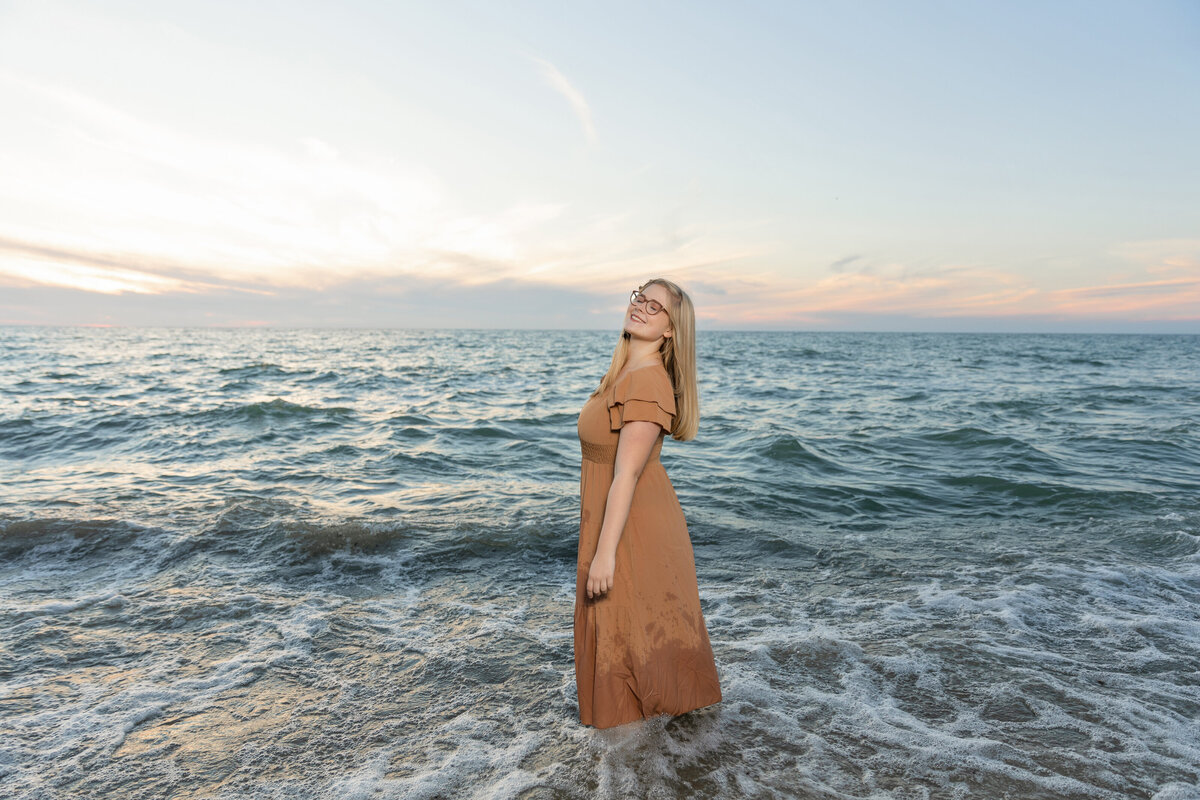 Senior photo of a girl standing in Lake Erie twirling around