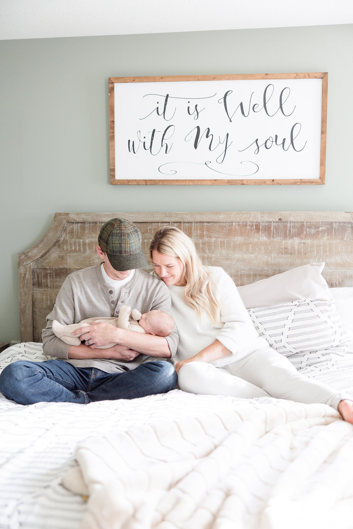 mom and dad smiling at newborn baby on master bed