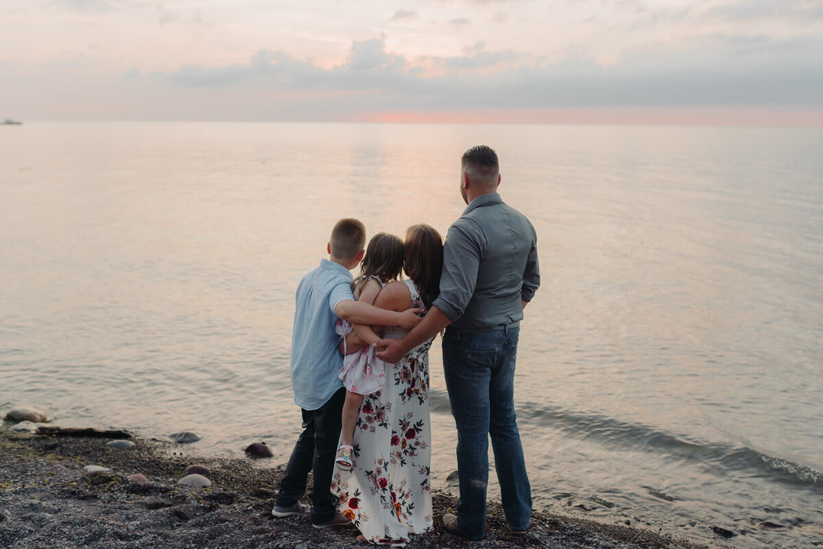 Family looking out at the lake at sunset at family with two kids on the beach at family photo shoot in Finger Lakes, NY