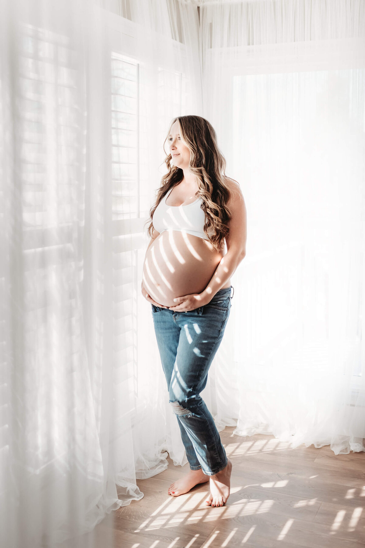 hard sunlight hitting pregnant woman in jeans and white sports bra