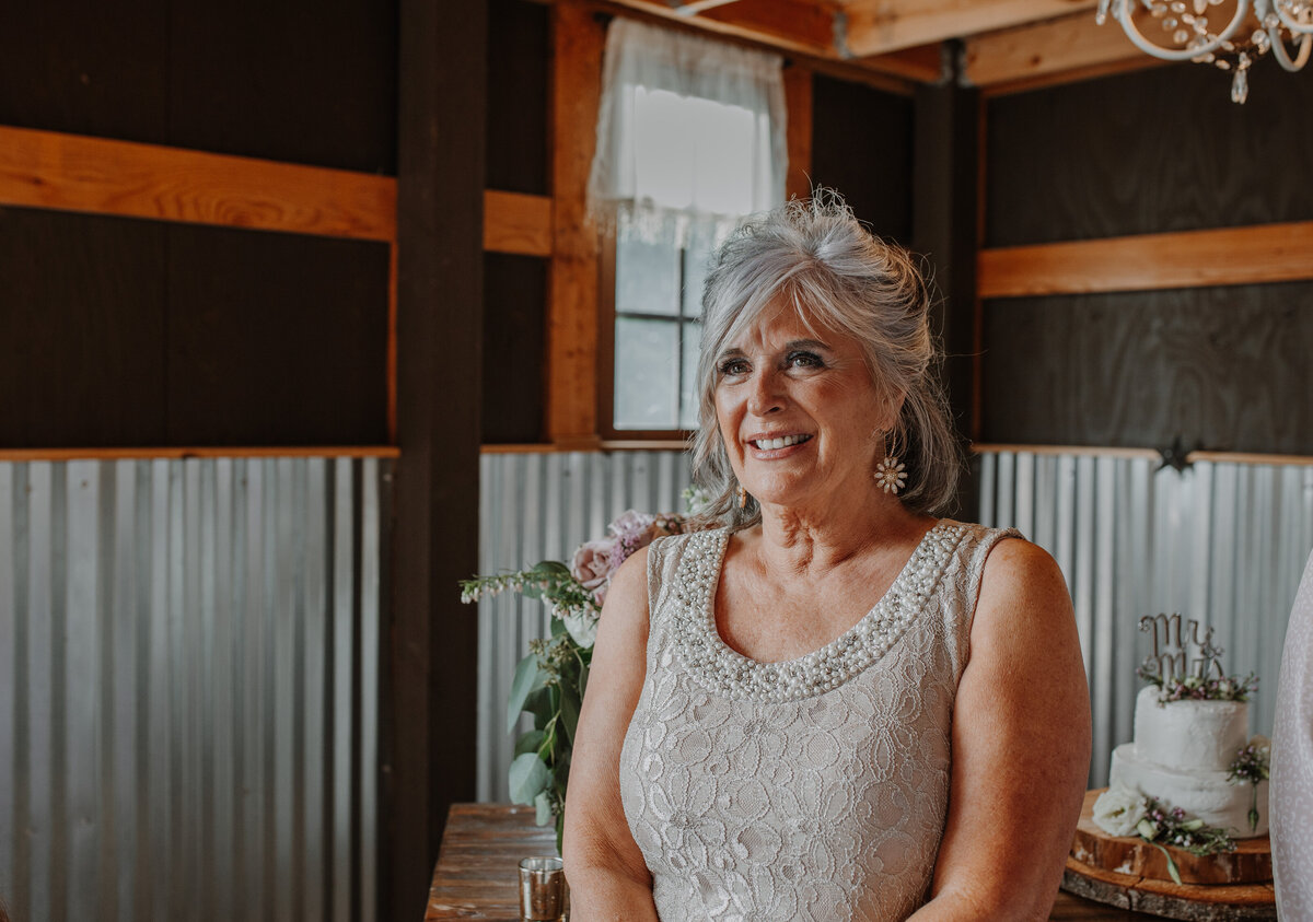 Lady with gray hair smiling in front of wedding cake