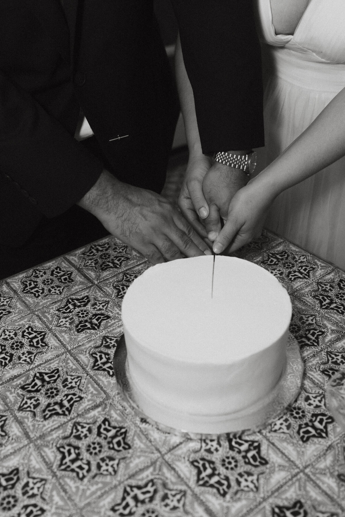 Black and white photo of a couple cutting their wedding cake 