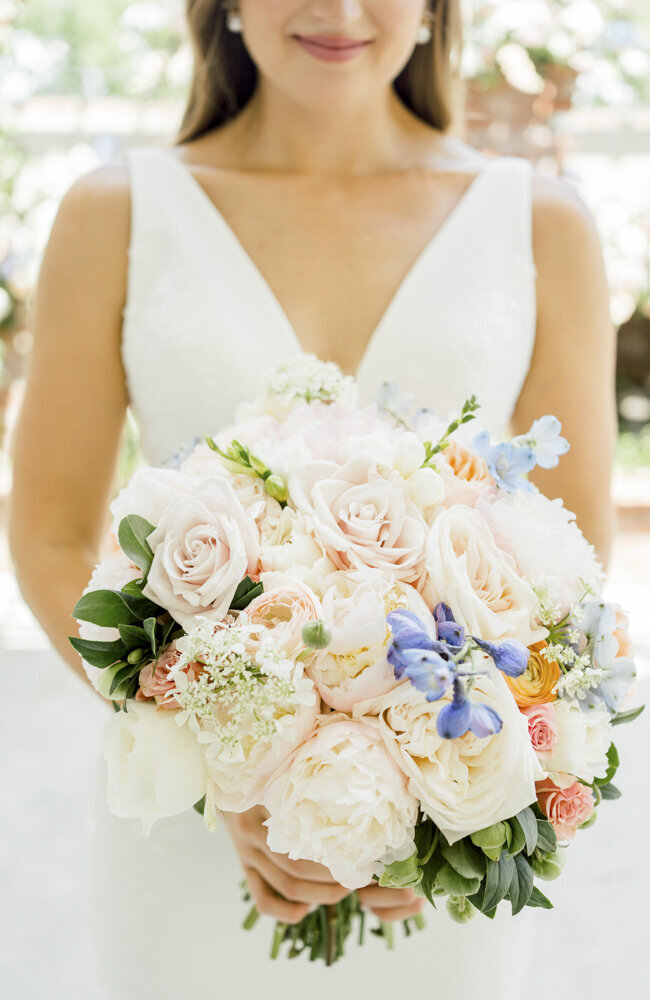 bride holding a bouquet of blue and pink flowers