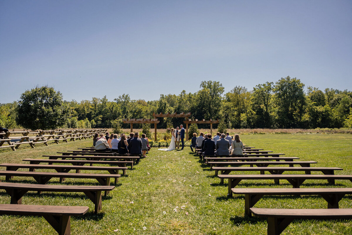 Wide view of ceremony setup with benches facing the pergola