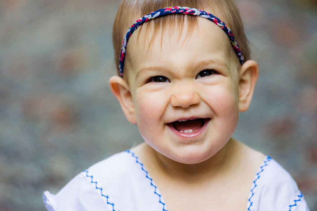 A child smiles with a headband that's braided.