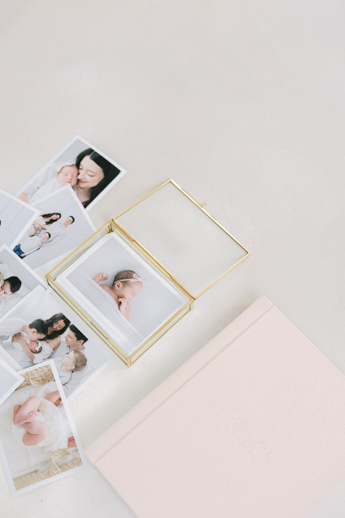 Flat lay image of a pink linen album next to a stack of printed photos taken by kentucky newborn photographer missy marshall