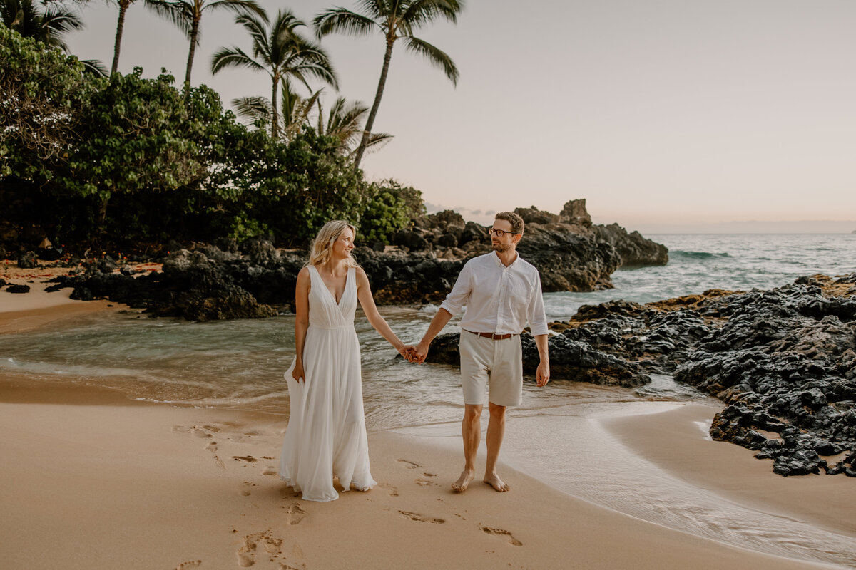 Maui Wedding Photographer captures groom holding bride's hand while walking on beach