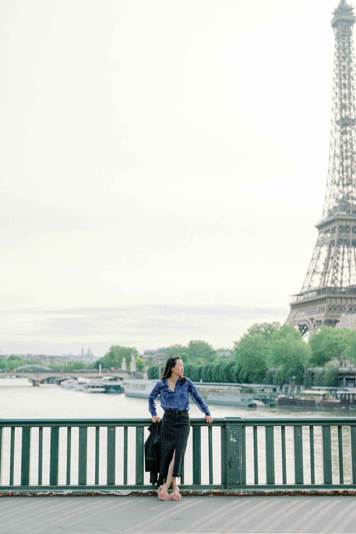 Kim-Trang stands in front of the Eiffel Tower and looks to her right