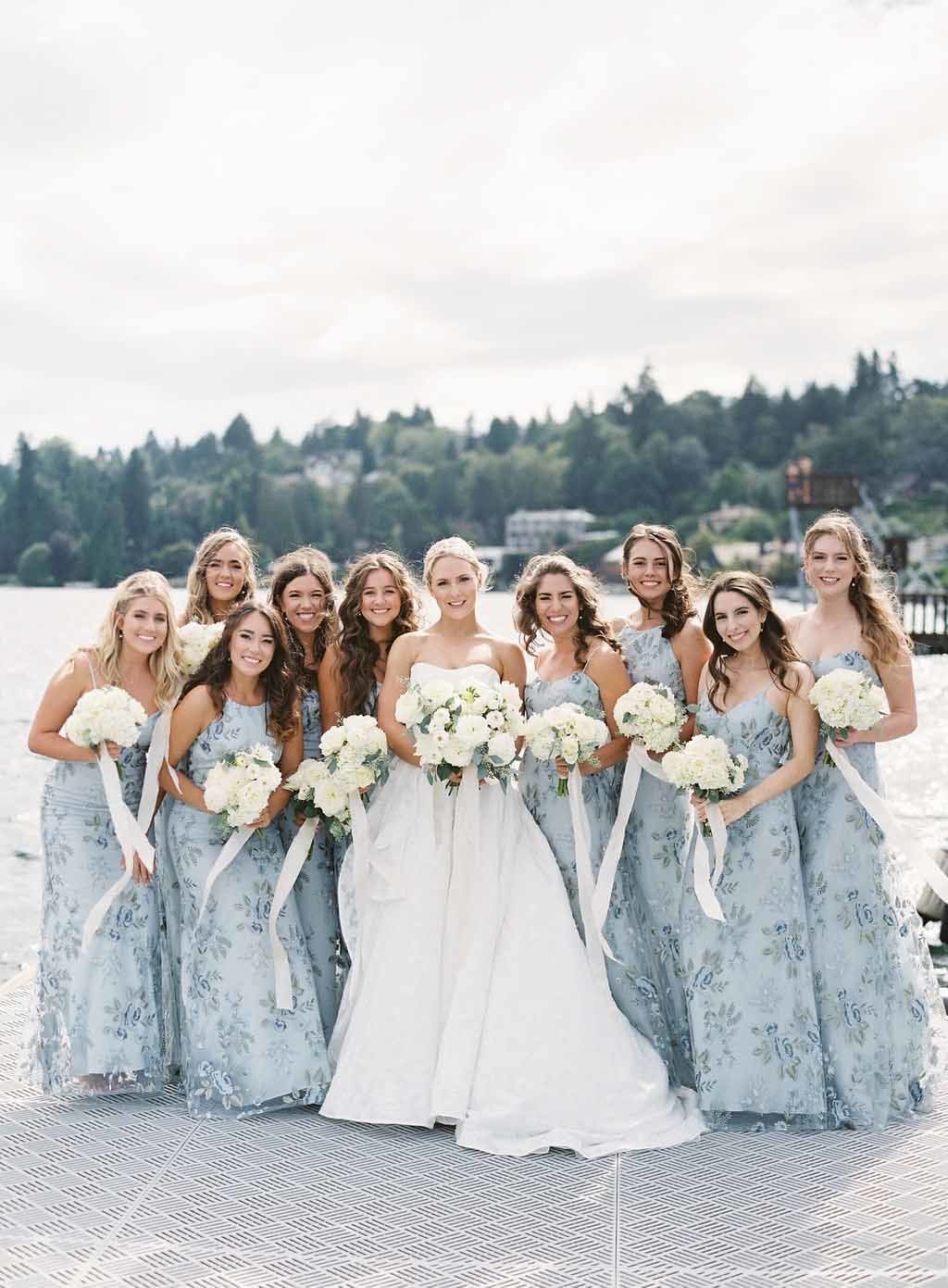 bride and her bridesmaids wearing long blue floral dresses holding white flower bouquets