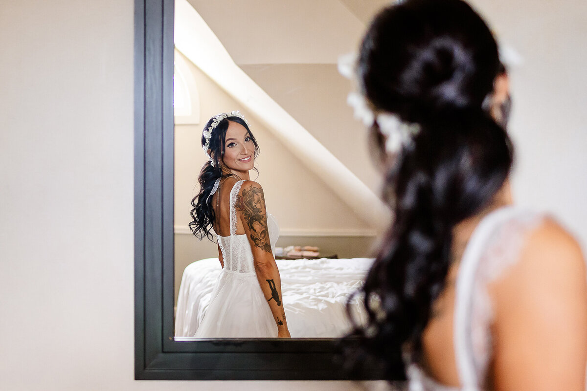 Joyful bride looking at herself in mirror